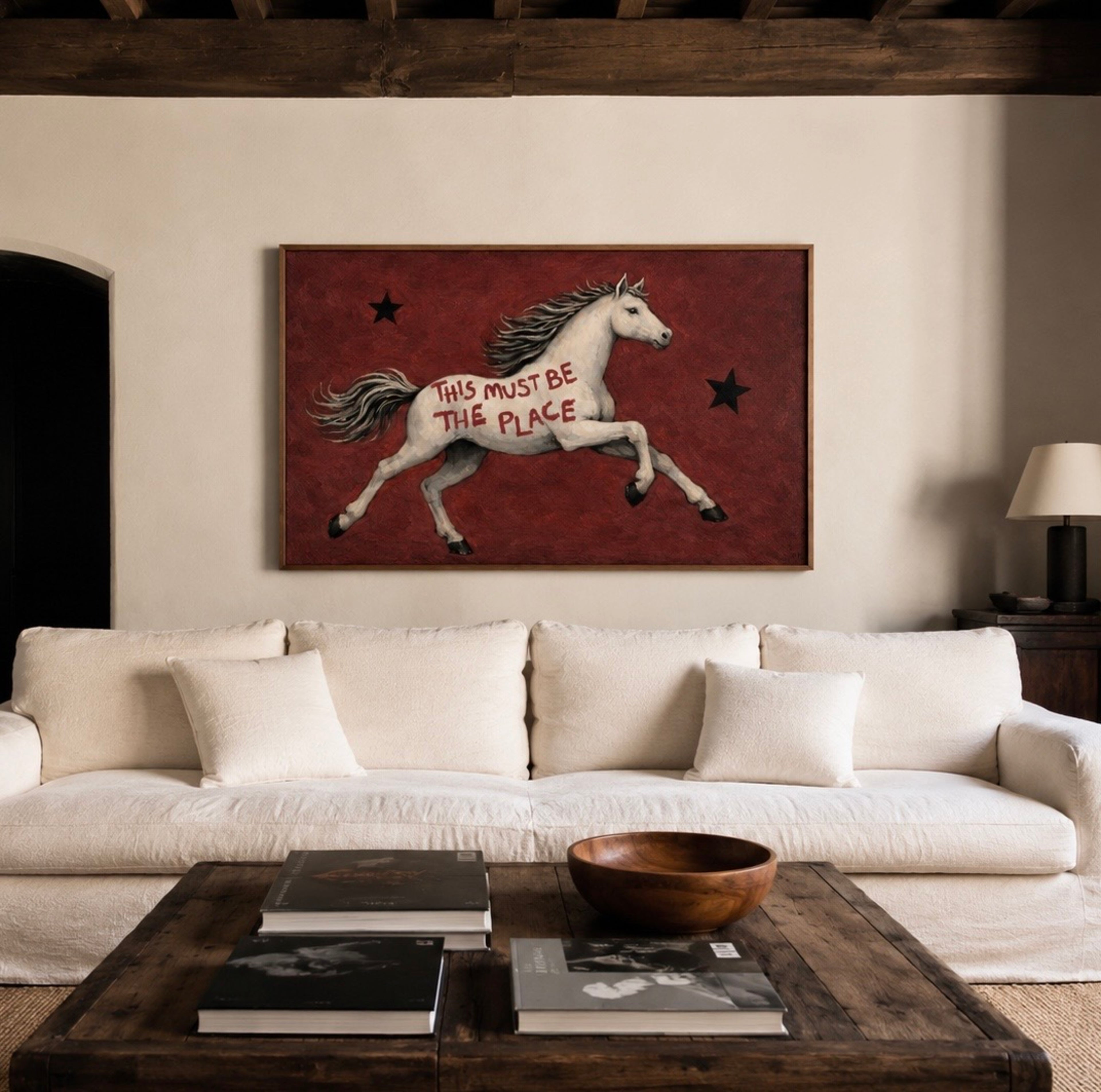 A surreal Symbolic artwork featuring a White Horse running against a rich burgundy background with black stars. The Horse has handwritten quote "This Must Be The Place". This is a hand drawn Contemporary Folk art Print Oil Painting.