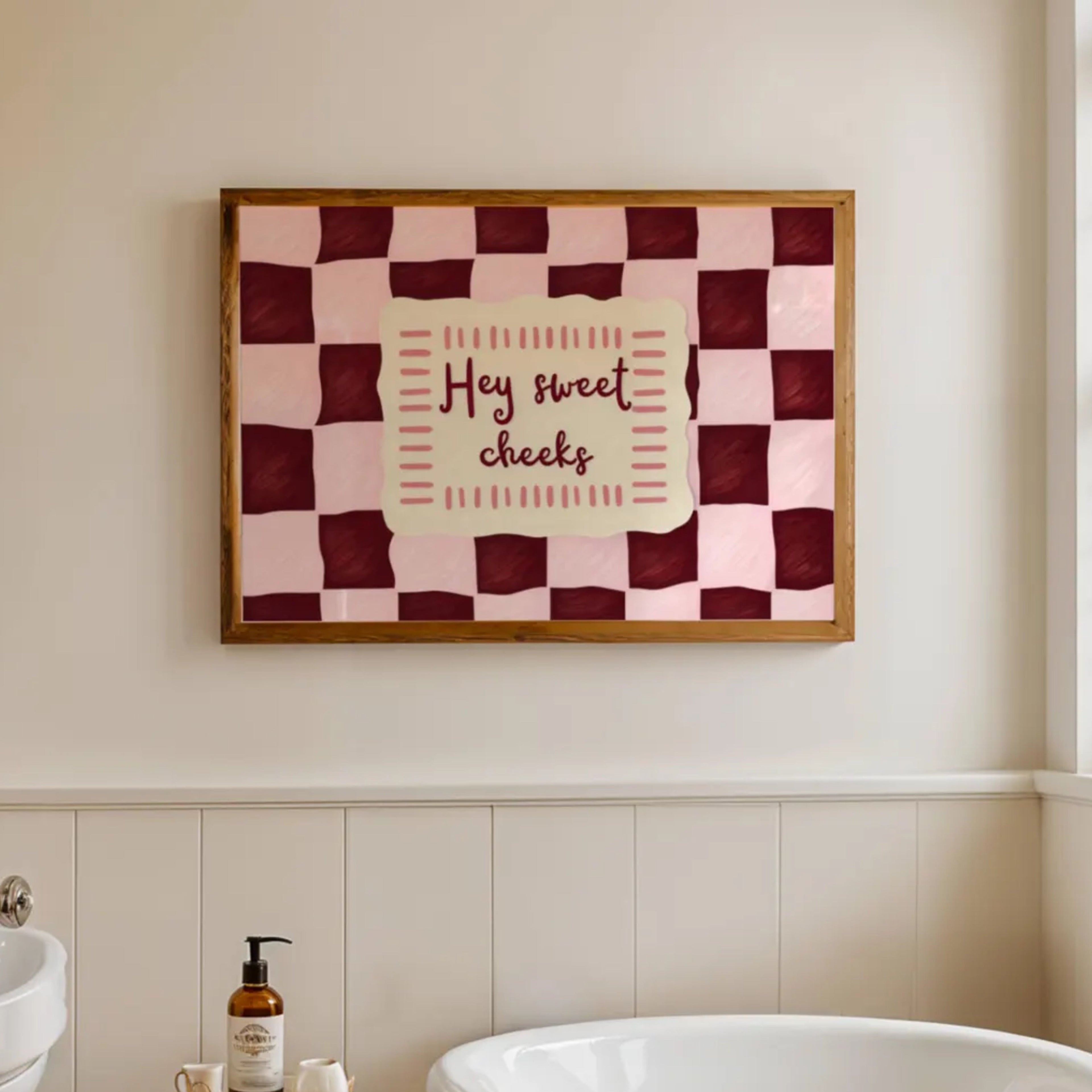 HEY SWEET CHEEKS is a whimsical Retro typography art print designed to bring humour, colour and personality into your bathroom and laundry room. Featuring vintage-inspired Checkered patterns and hand-lettered typography, this artwork captures the nostalgic charm while adding a playful decorative touch to modern interiors. this is a hand drawn Retro quote wall art, ideal for bathrooms, laundry room decor, and cheeky playful interiors. pink burgundy