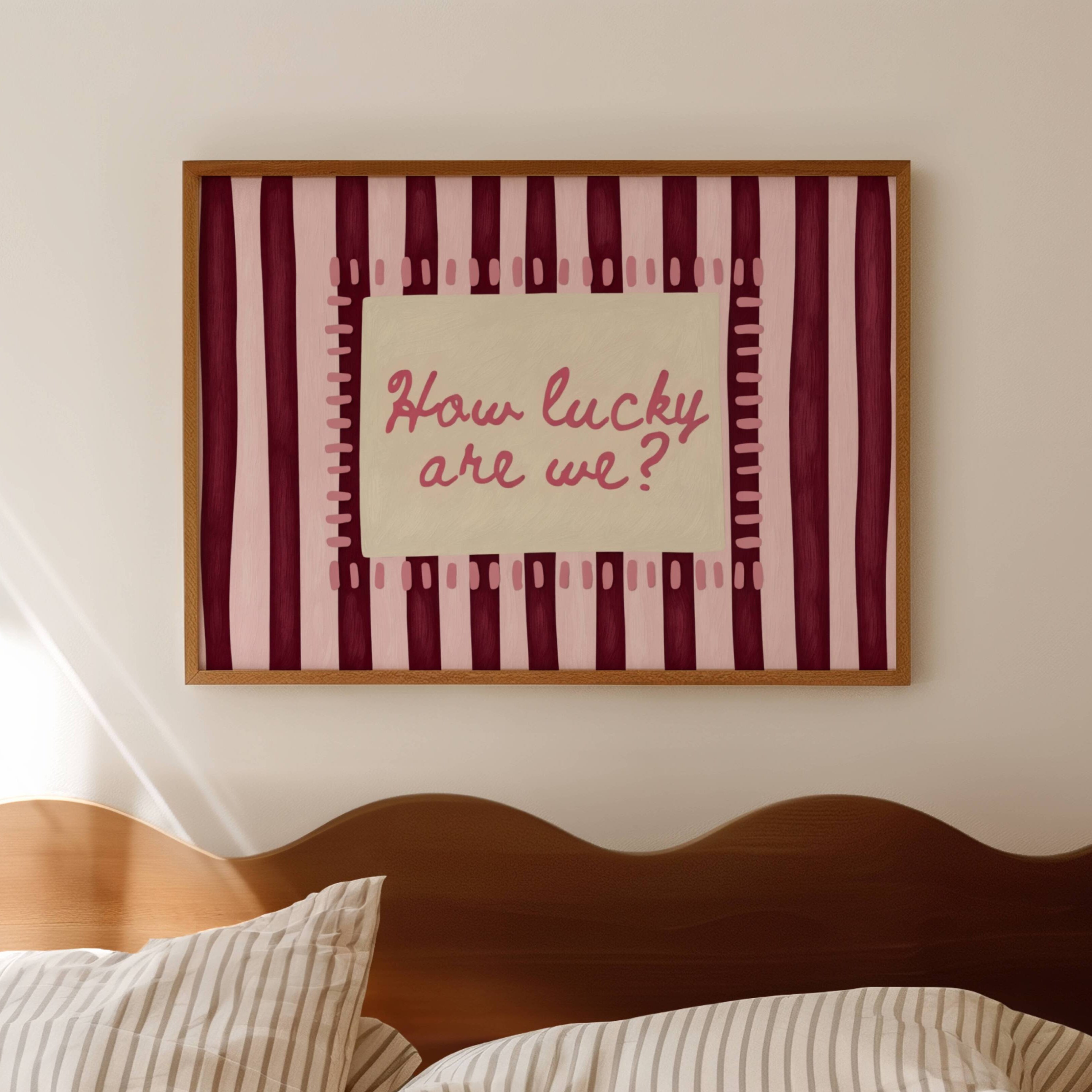 hand drawn Playful typography print with the phrase "How Lucky Are We?" on a pink and ruby burgundy striped background. This is a hand drawn trendy typography wall art print ideal for bedrooms, dorm room decor, gallery walls and playful interiors.