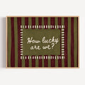hand drawn Playful typography print with the phrase "How Lucky Are We?" on a khaki and ruby burgundy striped background. This is a hand drawn trendy typography wall art print ideal for bedrooms, dorm room decor, gallery walls and playful interiors.