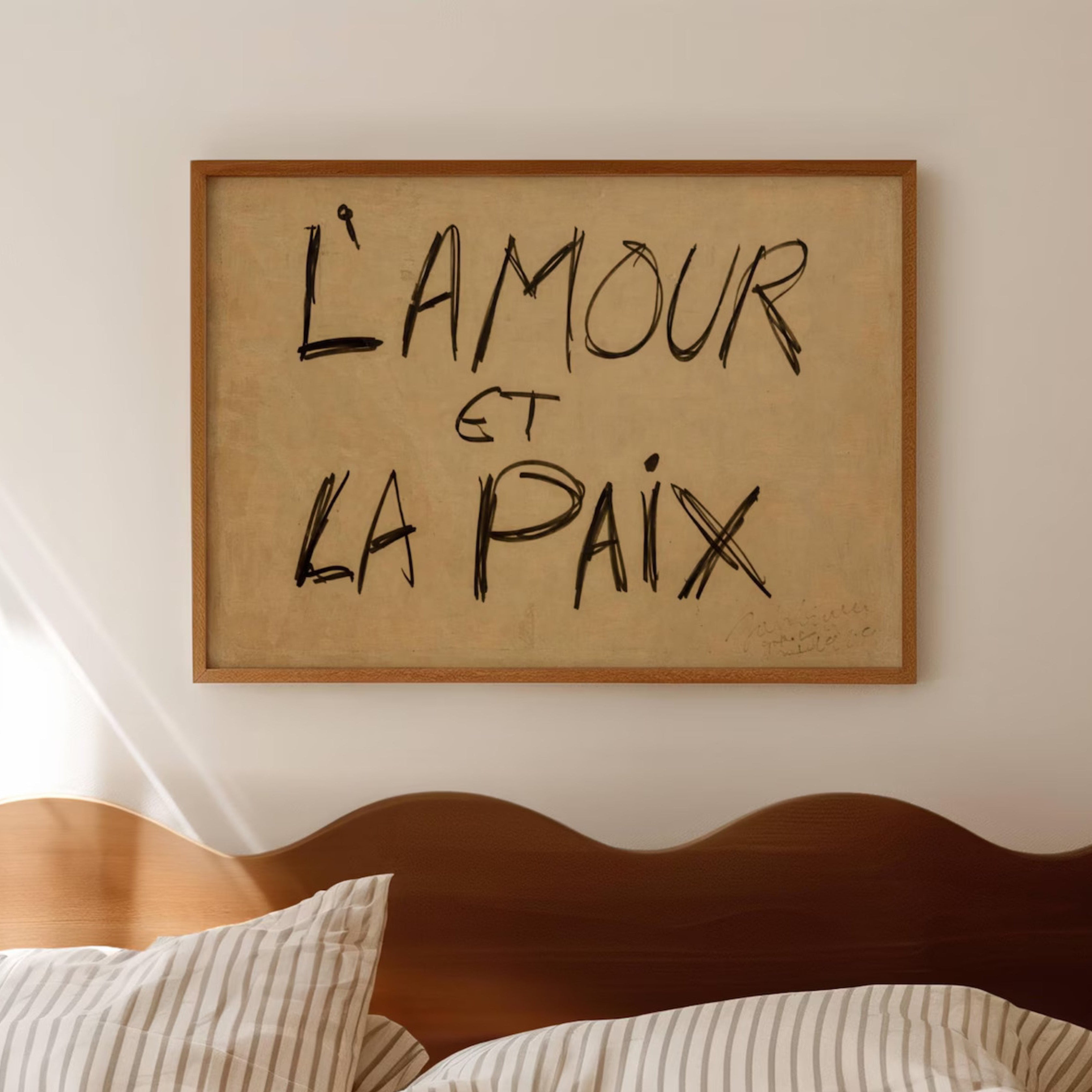 Framed artwork with 'L'Amour et La Paix' text above a bed.