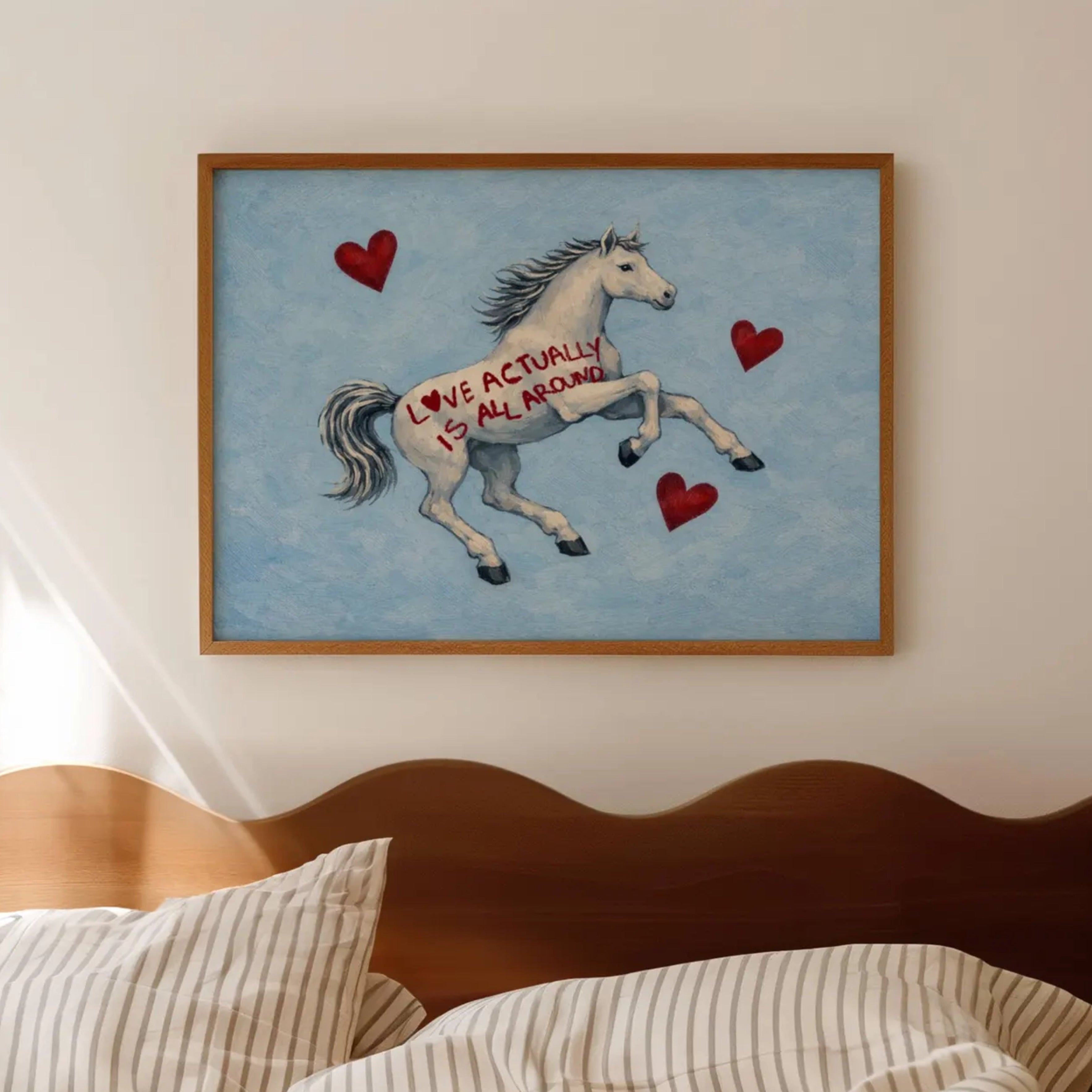 Symbolic Eclectic White Horse with red hearts and handwritten quote "Love Actually is All Around" on a soft blue background. This is a hand drawn Contemporary Folk art Print Oil Painting.