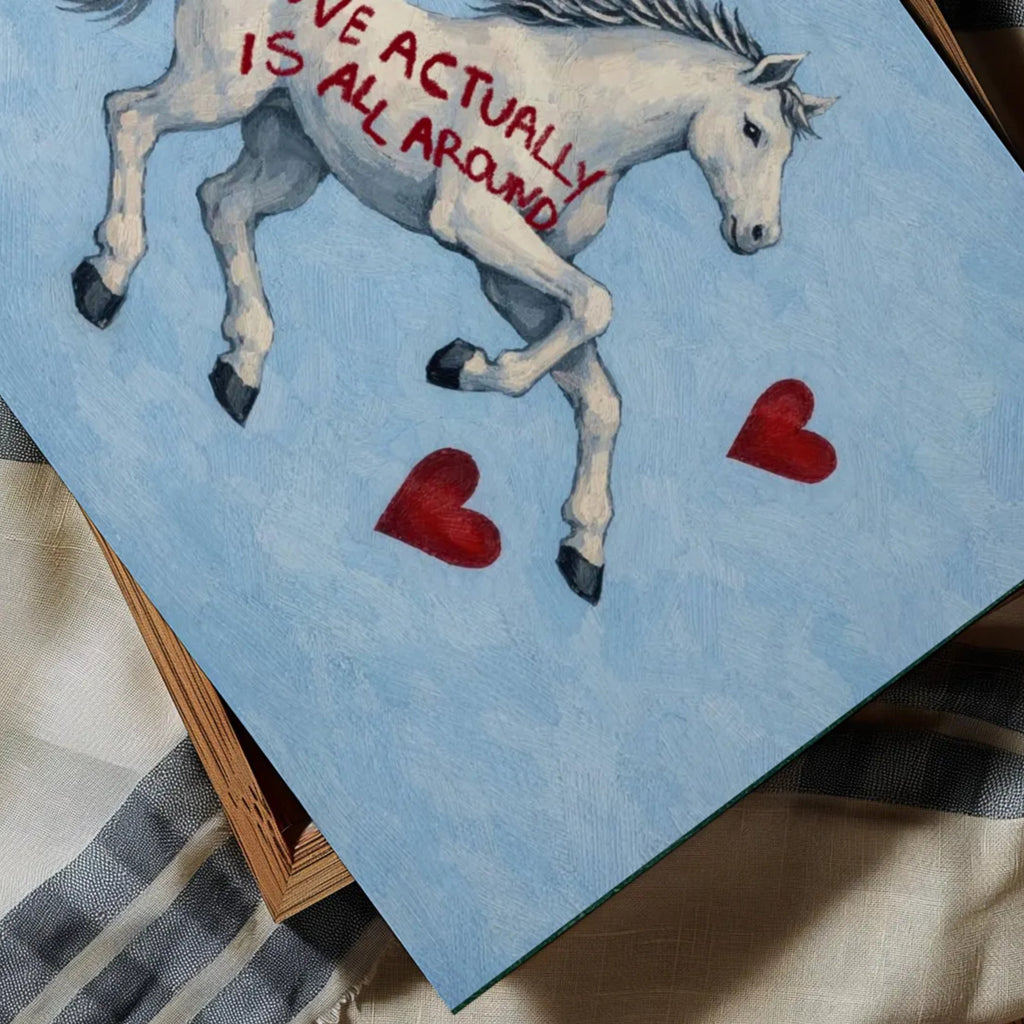 Symbolic Eclectic White Horse with red hearts and handwritten quote "Love Actually is All Around" on a soft blue background. This is a hand drawn Contemporary Folk art Print Oil Painting