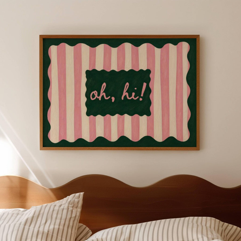 Framed artwork with pink and green striped border and 'oh, hi!' text above a bed.
