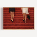 The red Staircase is a hand painted Contemporary and figurative wall art of two women descending deep red stairs, inspired by European cinema and nostalgic mid century aesthetics, against a red background with expressive painterly texture. Minimalist Feminine Mid century modern oil painting in cinematic nostalgia composition.