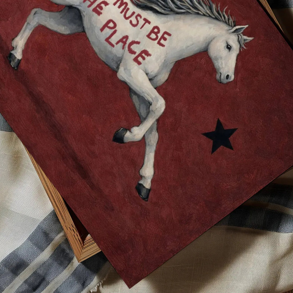 A surreal Symbolic artwork featuring a White Horse running against a rich burgundy background with black stars. The Horse has handwritten quote "This Must Be The Place". This is a hand drawn Contemporary Folk art Print Oil Painting.