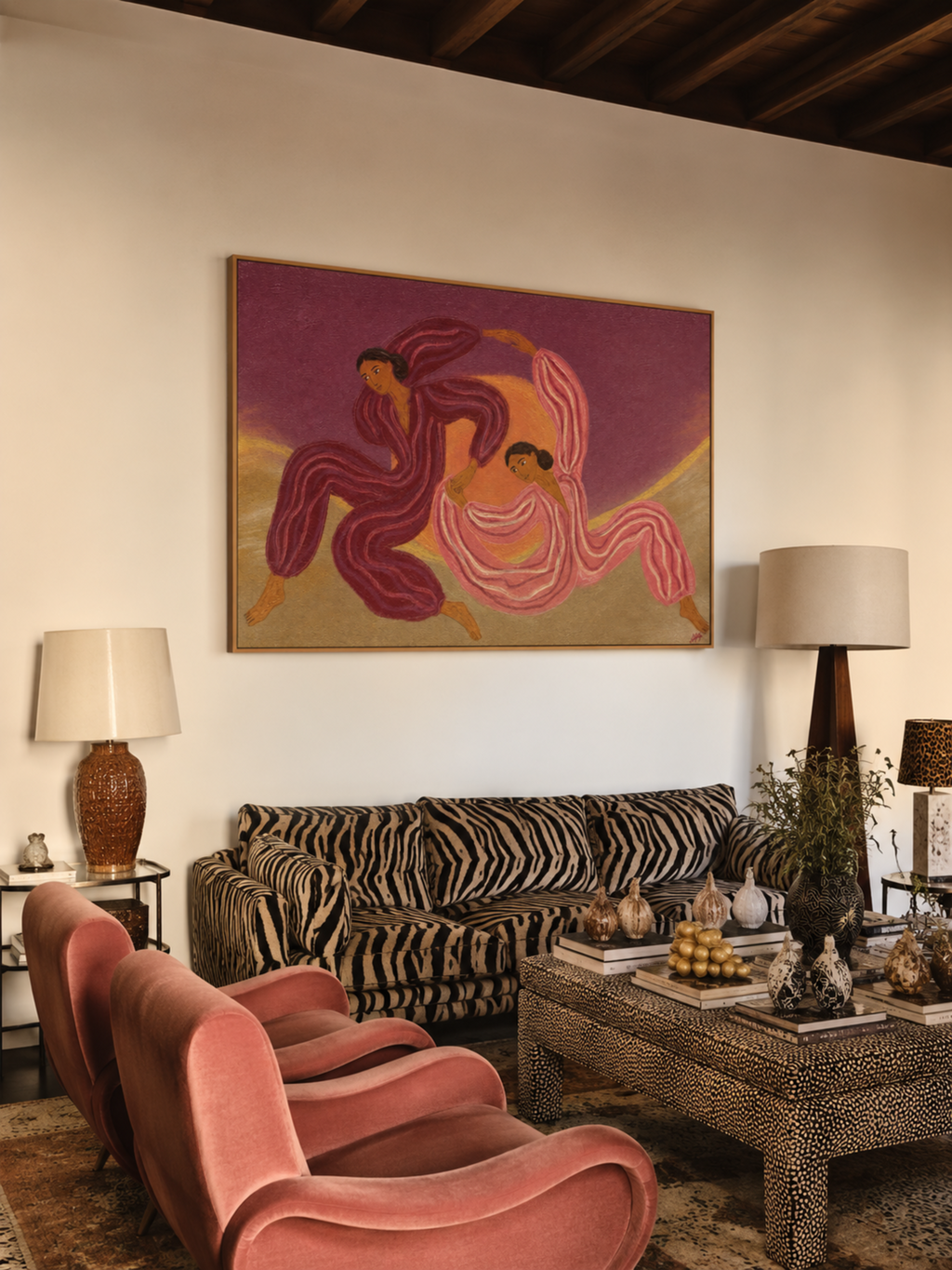 A framed art print depicting two dancing figures in pink and purple hues, displayed on a beige wall in a modern living room setting with a zebra-print sofa and pink velvet chairs.