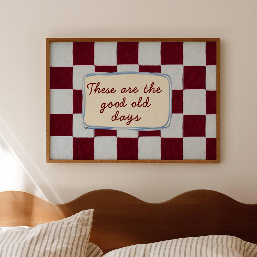 Framed checkered artwork with 'These are the good old days' text above a bed.