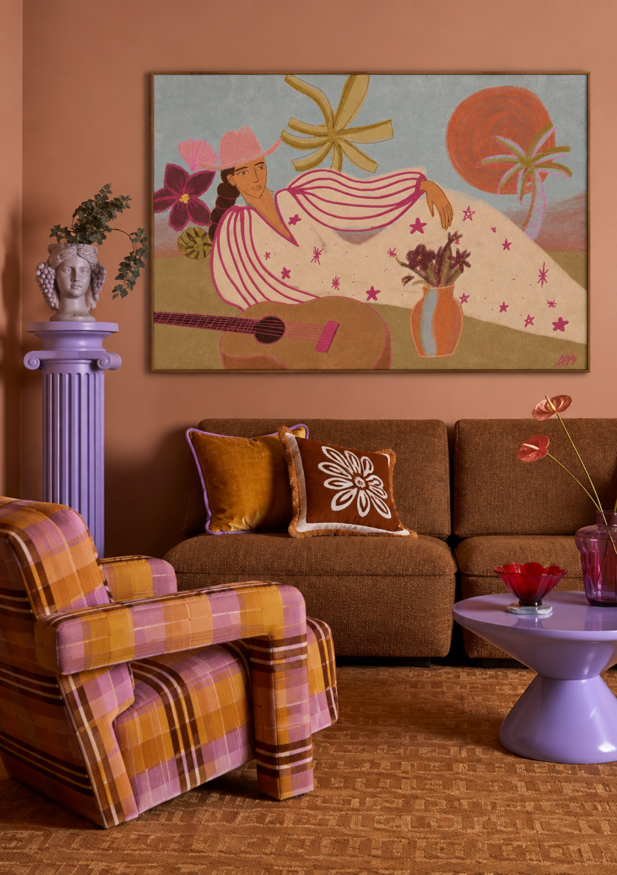 A framed art print featuring a retro-style illustration of a woman with a guitar and flowers, displayed on a terracotta wall above a brown sofa in a styled living room.